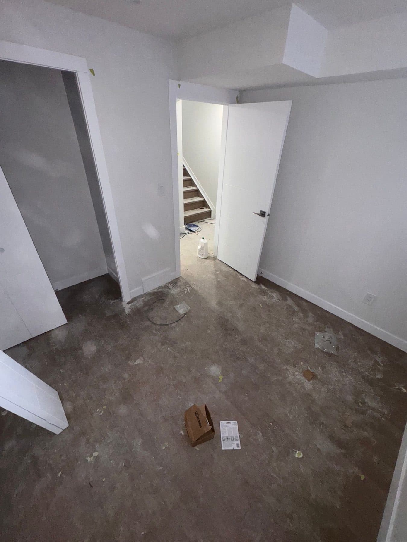 Suite landing during construction with debris on the floor and dust across the walls and stair opening.