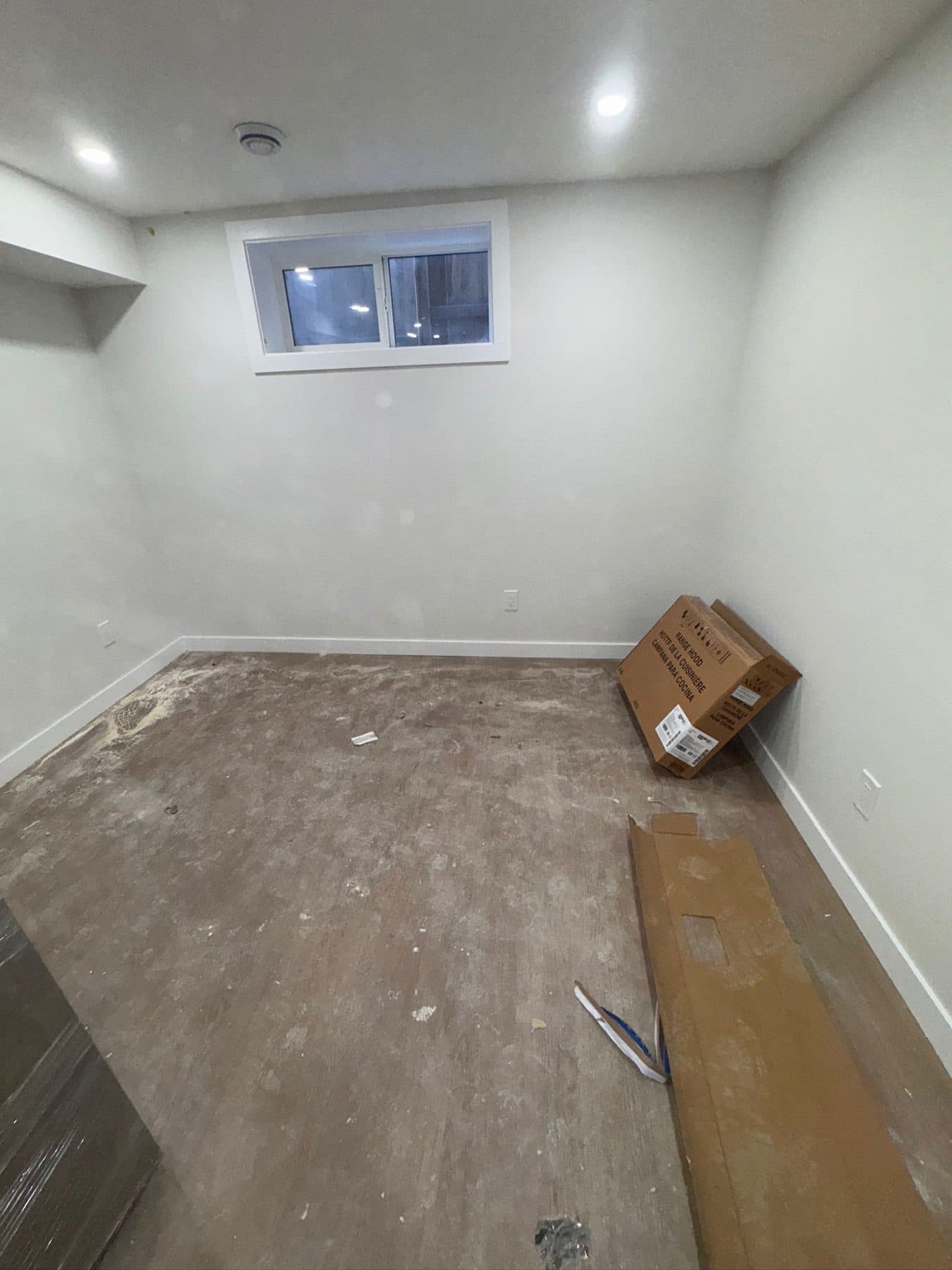 Storage room during construction with packaging and offcuts left on a bare concrete floor.