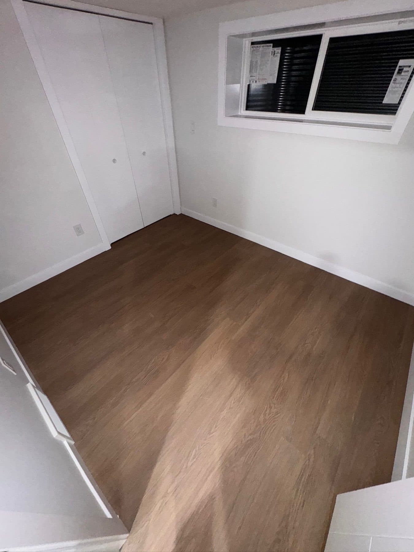 Finished basement bedroom with closet doors, egress window and new flooring, cleaned for handover.