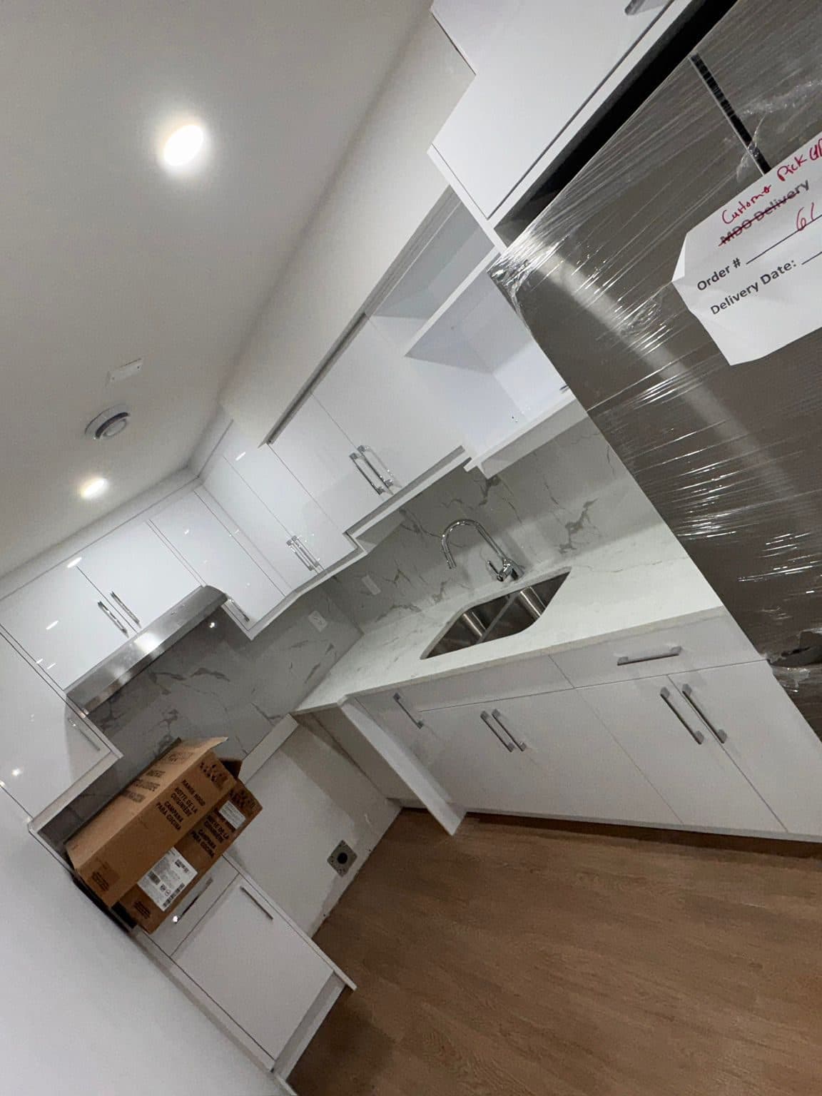 The same suite kitchen at handover: film removed, cabinets, counters and appliance fronts cleaned, floor finished.